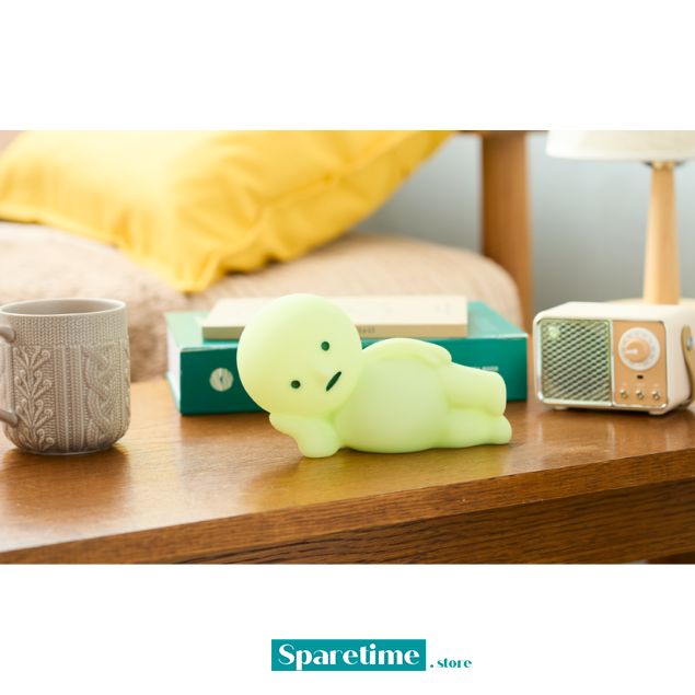 Glowing green plush toy on a wooden surface with a mug, book, and lamp in the background. SMISKI Touch Light vol.2