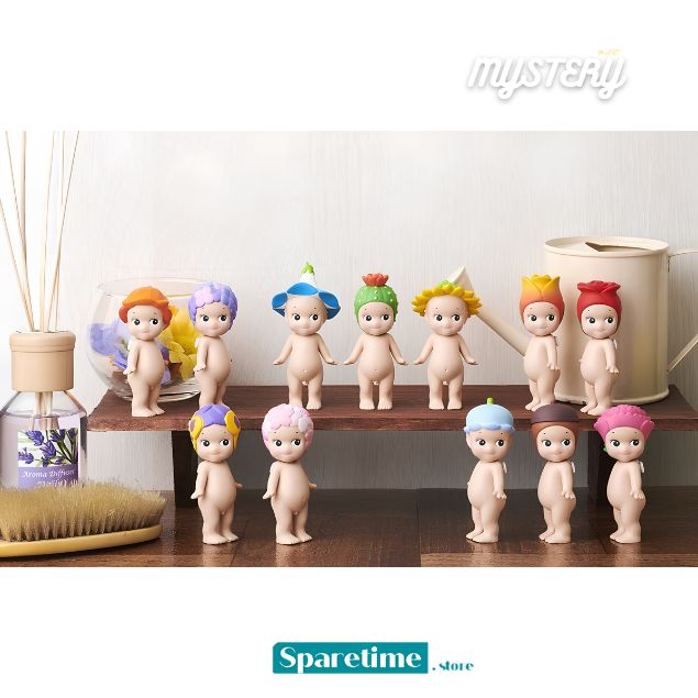 A set of small collectible character figurines posed on a wooden shelf in a styled interior scene, with a diffuser, brush, and watering can visible around them. The figures have pale peach skin and colorful hair or hat accents in orange, purple, blue, green, yellow, and red.
